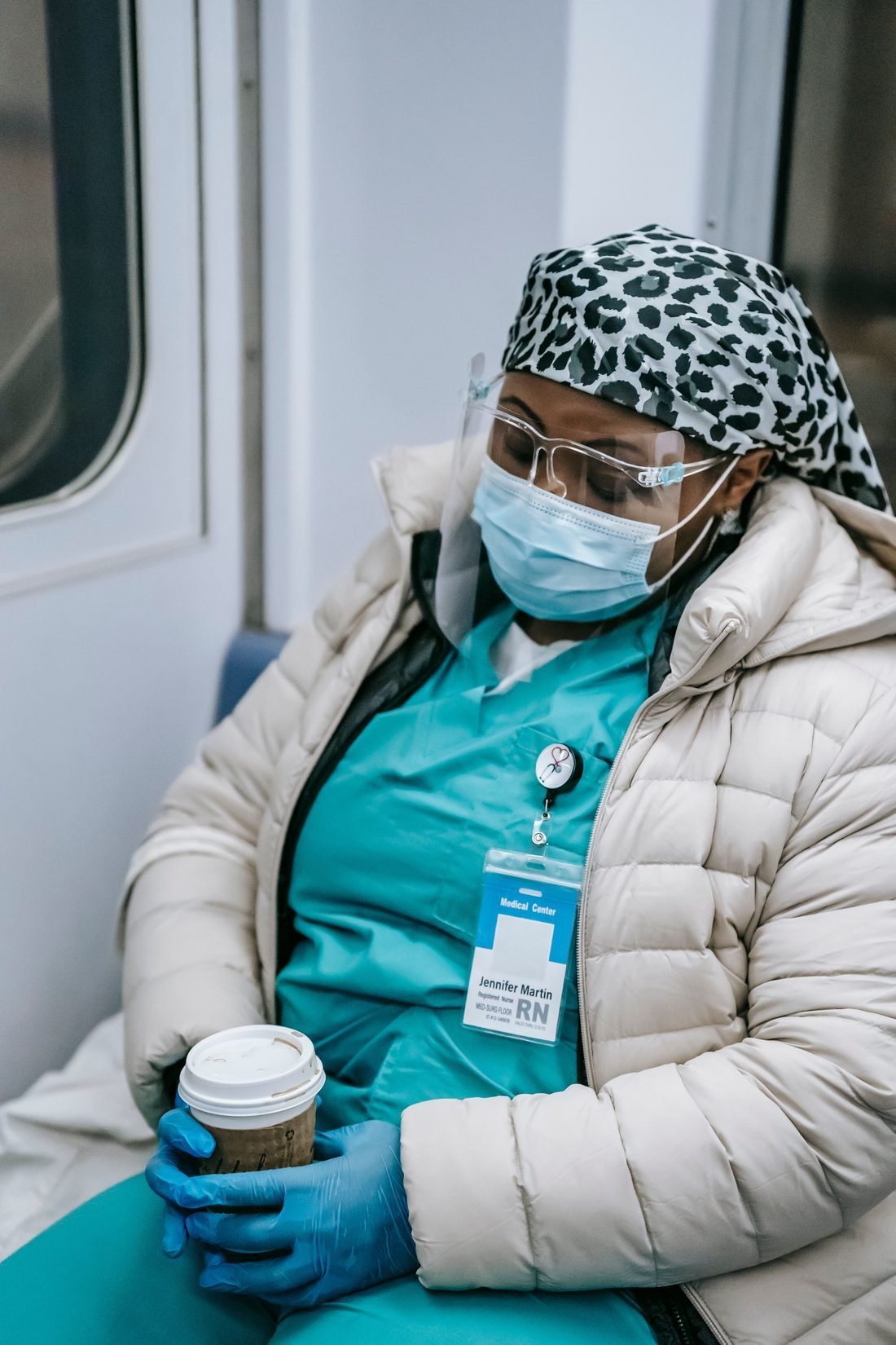 A nurse resting on her commute home, holding a cup of coffee