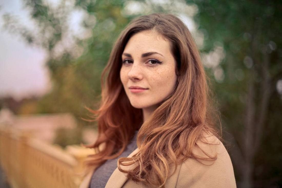 A woman outdoors in soft afternoon light, looking toward the horizon